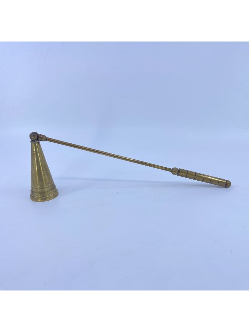 vintage brass candle snuffer with conical base and a long, slender brass handle